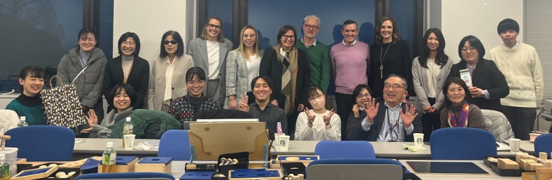 Gruppenfoto der Besucherinnen von der Nikolauspflege mit Studierenden und Professorinnen und Professoren der Universität von Tsukuba in einem Klassenzimmer der Universität. Im Vordergrund ist taktiles Material aufgebaut. Als Vertreterinnen der Nikolauspflege waren Anne Reichmann, die Vorstandsvorsitzende der Nikolauspflege, Sabrina Betz, die stellvertretende Schulleiterin des Betty-Hirsch-Schulzentrums, und Frederike Isenberg, die Leiterin des Sonderpädagogischen Dienstes, anwesend.