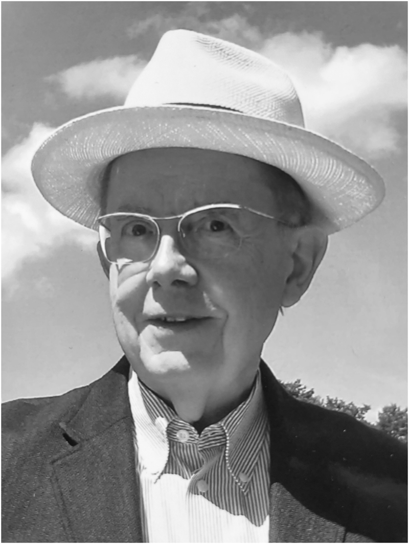 Das schwarz-weiße Foto zeigt ein Porträt von Dr. Klaus Schreck. Er trägt Anzug, Hemd und Sonnenhut sowie seine „Schreck-Brille“. Aufmerksam schaut er in die Kamera.
