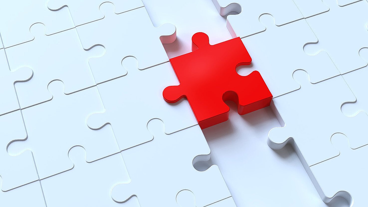 Nahaufnahme eines weißen Puzzlefeldes mit einer einzelnen roten Puzzleteil, das deutlich hervorsticht und fast vollständig in die vorgesehene Lücke eingefügt ist.