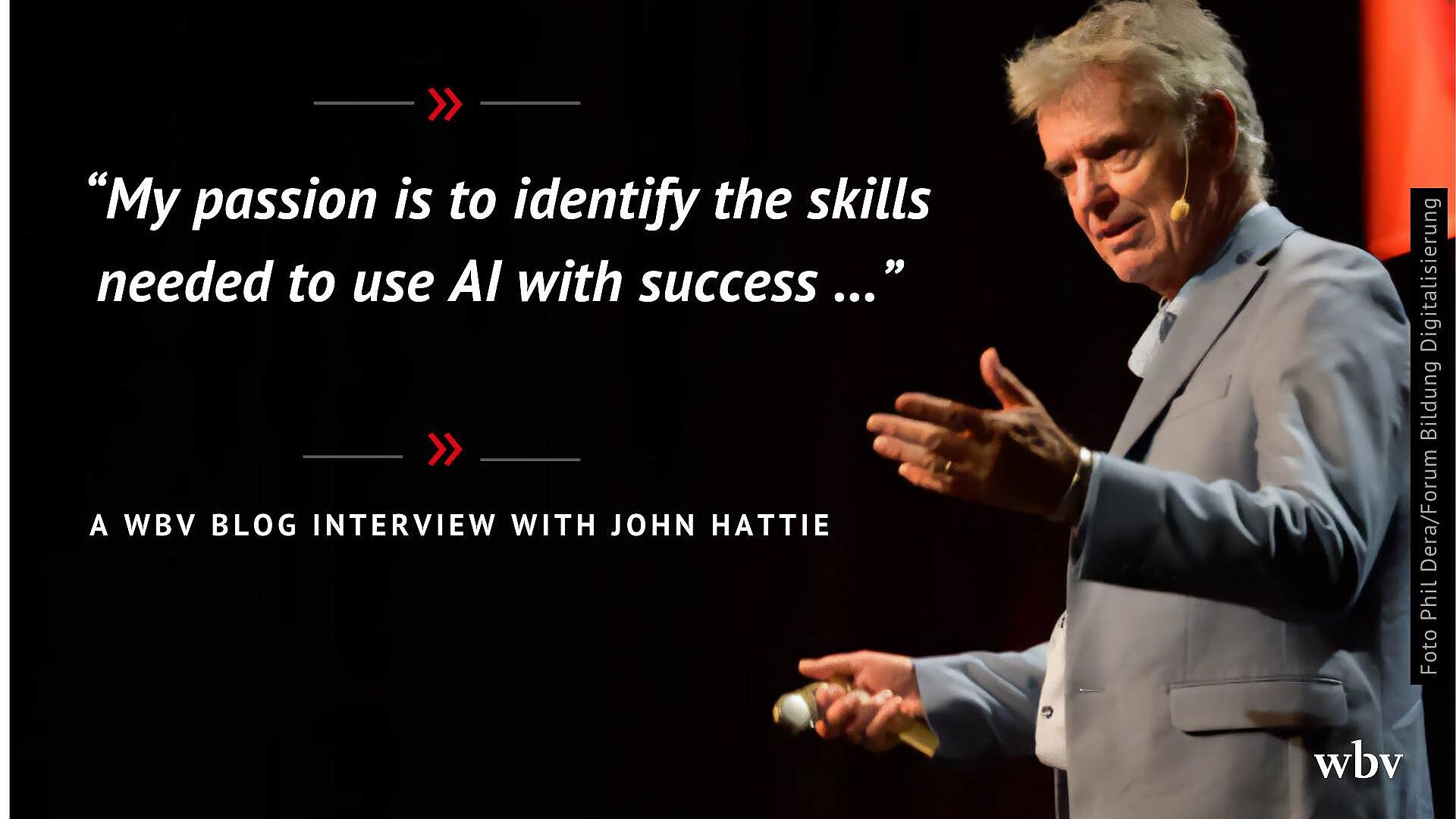 Auf dem Bild ist eine dunkle Bühne zu sehen, auf der ein elegant gekleideter Redner im hellen Anzug mit Mikrofon in der Hand steht und gestikulierend spricht. Links im Bild steht in großer weißer Schrift das Zitat „My passion is to identify the skills needed to use AI with success …“, eingerahmt von roten Doppelpfeilen. Darunter befindet sich der Hinweis „A wbv blog interview with John Hattie“, außerdem sind am rechten Rand ein Foto-Credit sowie unten rechts das wbv-Logo platziert.